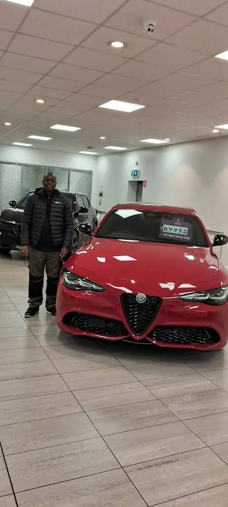 Man beside a red car inside a showroom