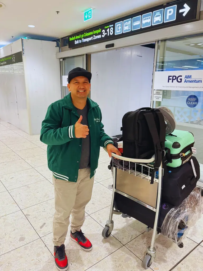 Smiling traveller with a luggage trolley at the airport